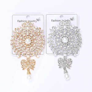Detail of baroque pearl and rhinestone brooches in gold and silver finish with teardrops