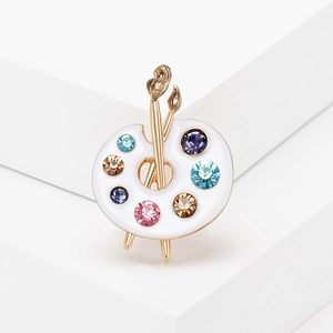 Artistic palette brooch with golden paintbrushes and colorful rhinestones on stone pedestals
