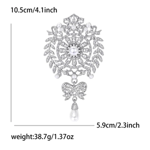 Detailed view of luxury brooch with rhinestones and pearl pendant, 10.5cm by 5.9cm