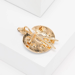 Detailed back view of golden artist palette brooch with brushes and safety pin clasp