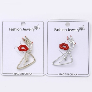 Détail de la broche lèvres rouges en émail et main avec métal poli sur carte de bijoux