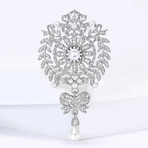 Elegant bow brooch with pearls and rhinestones on a white minimalist background
