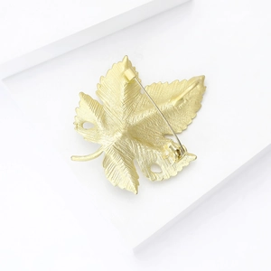 Détail de l'arrière d'une broche feuille d'or avec fermoir de sécurité et texture brossée