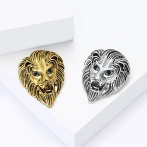 Retro lion head brooch with green gemstone eyes on white geometric display stand