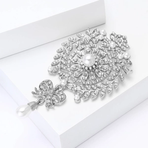 Detailed close-up of bow brooch featuring white pearls and rhinestones on a white block