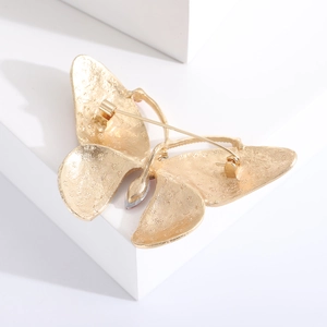 Detailed back view of a golden butterfly brooch with star embossing and safety pin