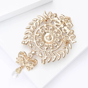 Macro view of gold brooch back showing secure pin clasp, bow, and pearl pendant detail