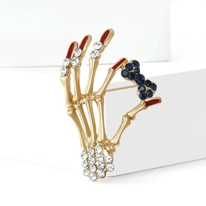Vintage skeleton hand brooch with gold metal finish and blue rhinestone bow ornament
