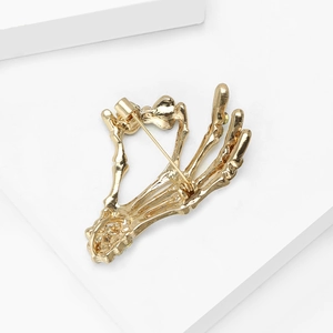 Detail of a vintage golden alloy skull hand brooch with back pin buckle and metallic finish