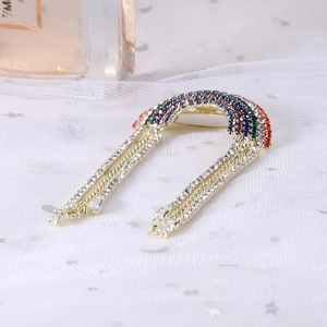 Close-up of golden rainbow brooch with colorful rhinestones and dangling fringe chains