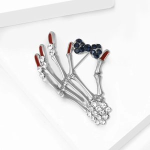 Detailed macro view of skull hand brooch with blue crystal bow and clear rhinestones