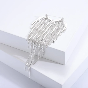 Détail d'une broche cœur argentée ornée de strass brillants et de glands élégants