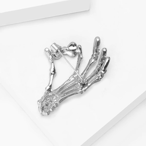 Detail view of gothic skull hand brooch back showing secure silver safety pin clasp