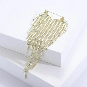 Détail d'une broche cœur dorée avec de longs glands en cristal sur un support géométrique