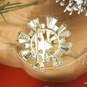 Élégante broche flocon de neige dorée avec strass sur un fond rouge festif