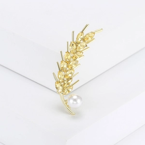 Macro shot of gold wheat brooch with yellow crystals and elegant white pearl detail