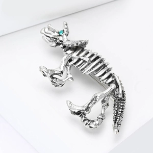 Macro shot of vintage silver dinosaur skeleton brooch with a bright green gemstone eye