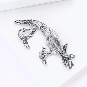 Detailed close-up of retro silver dinosaur skeleton brooch with green crystal eye