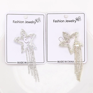 Detailed view of silver and gold star tassel earrings with rhinestones on a display card