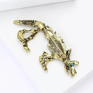 Dettaglio della spilla a forma di lucertola vintage con occhi di strass verdi e finitura oro