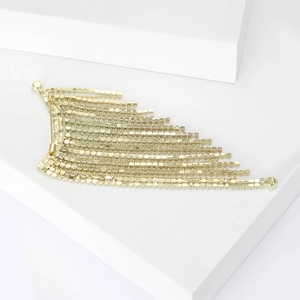 Elegant gold tassel brooch with sparkling rhinestones displayed on a geometric block