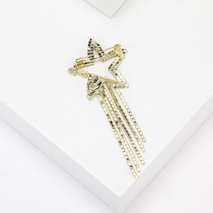 Detail of a gold star brooch featuring hollow lines and long chain tassels on a white base
