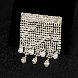 Détail de l'élégante broche à pompon en strass dorés avec cristaux en forme de poire sur noir