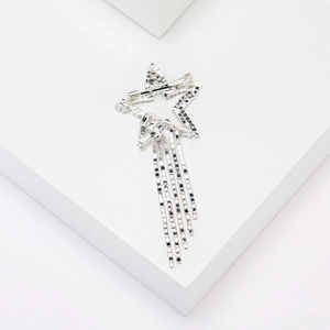 Detailed close-up of a silver star tassel brooch with rhinestones on a white cube