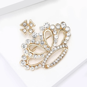 Élégante broche couronne dorée avec strass blancs étincelants sur support d'affichage blanc