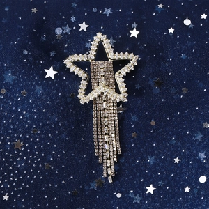 Detailed close-up of sparkling star brooch with crystal tassels on blue star fabric