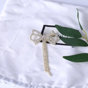 Spilla a fiocco scintillante con lunghe nappe di strass su base in metallo dorato