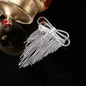 Elegant silver bow brooch with hanging fringe tassels on high-gloss black background