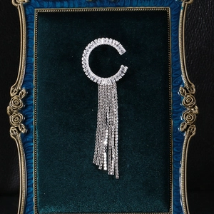 Détail de la broche lettre C avec de longs glands en cristal sur velours vert