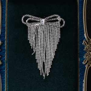 Detail of silver bow brooch with shimmering rhinestones and long tassel on green velvet