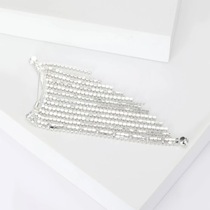 Close-up of geometric silver tassel brooch with sparkling crystal chains on white cube