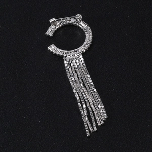 Élégante broche argentée en forme de C avec des pampilles en strass sur fond noir