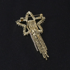 Sparkling star brooch with long rhinestone tassels and secure pin clasp on dark background