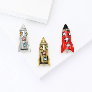 Three trendy alloy rocket brooches with rhinestones in gold, silver, and red enamel colors