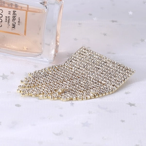 Detailed macro view of a sparkling crystal lip brooch with flowing diamond tassels on gold base