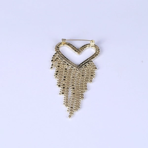 Broche cœur dorée élégante avec de longues franges métalliques sur fond bleu clair