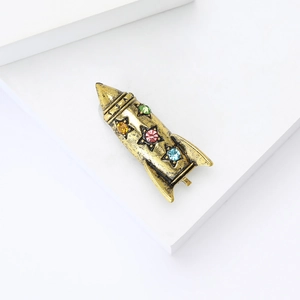 Close-up of vintage rocket brooch with antique gold finish and colorful rhinestones
