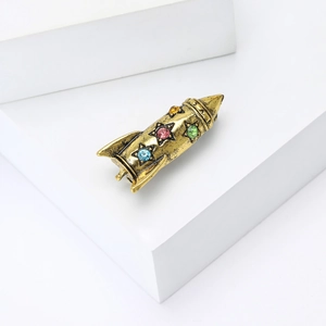 Macro shot of vintage gold rocket brooch with colorful star rhinestones on white stones