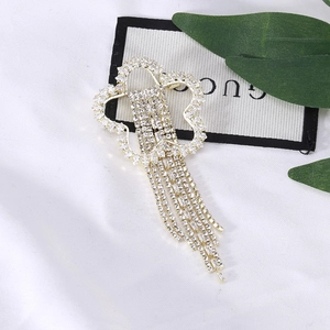 Broche fleur en strass étincelants avec longues chaînes à pompons sur soie blanche