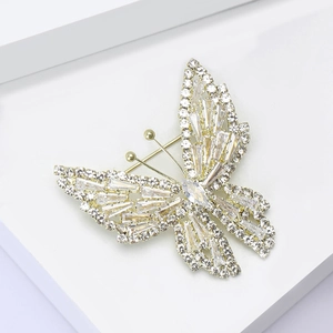Détail d'une broche papillon en or de luxe avec zircons baguettes sur un socle blanc