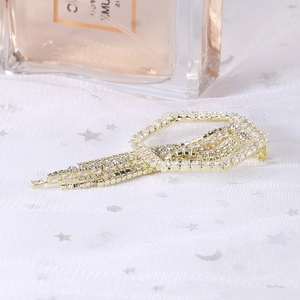 Macro detail of gold geometric brooch with sparkling rhinestone tassels on white tulle