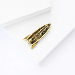 Detail view of vintage gold rocket brooch showing secure alloy pin clasp and metal texture