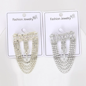 Detailed view of gold and silver layered tassel brooches with sparkling crystals