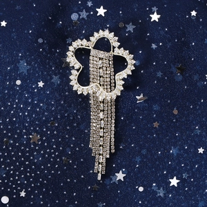 Gros plan d'une broche fleur dorée scintillante avec de longs glands en cristal sur bleu