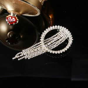 Broche élégante en cercle argenté avec de longs pompons scintillants et des zircons blancs