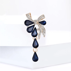 Broche élégante en forme de nœud doré avec cristal bleu profond et strass étincelants